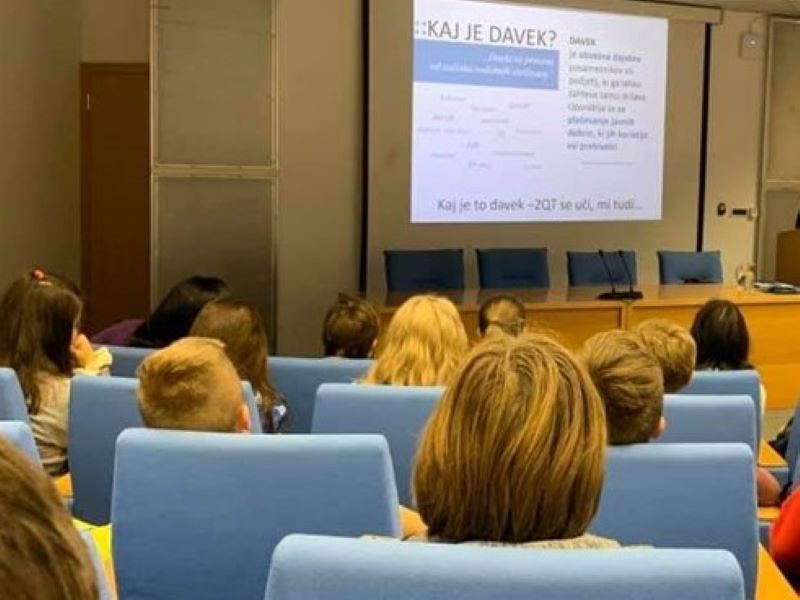 Mladi poslušalci v predavalnici gledajo na projektor.