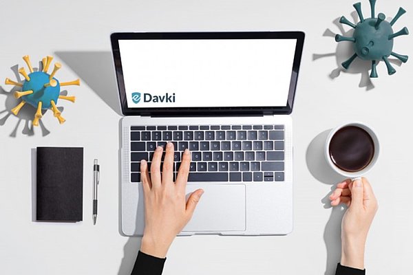  Ženska z levo roko tipka na notebook, v desni roki pa drži skodelico kave.