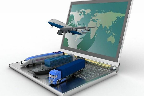  Notebook računalnik, na tipkovnici pa figurice različnih prevoznih sredstev (kamion, ladja, vlak, letalo).